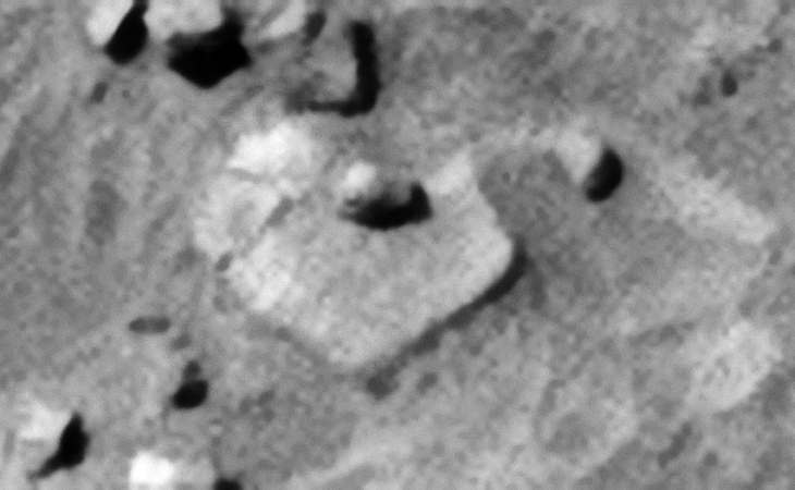Another strange feature or knob with small dome-shaped part in the center on top of a large, hexagonal-shaped slab with rounded corner