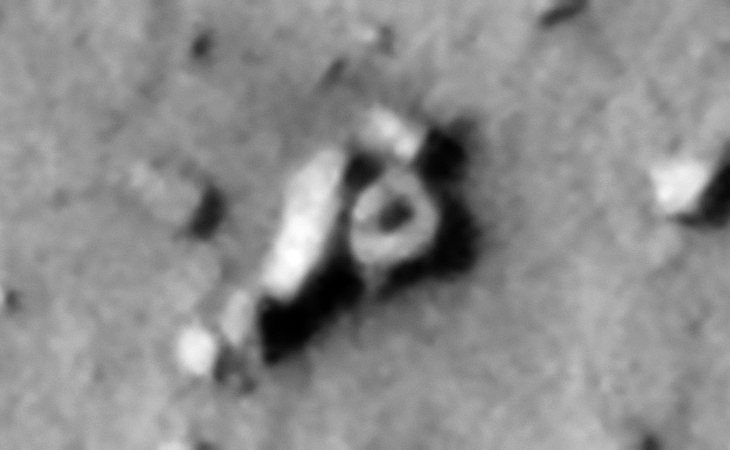 A smaller saucer-shaped craft next to what appears to be a wrecked hangar or entrance-way